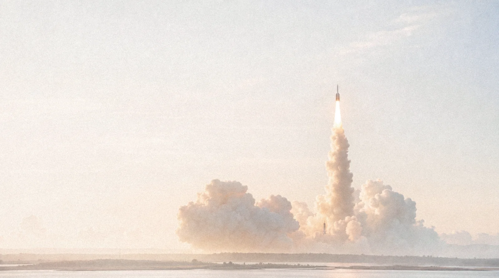 Rocket lifting through dawn cloud, soft cream sky.