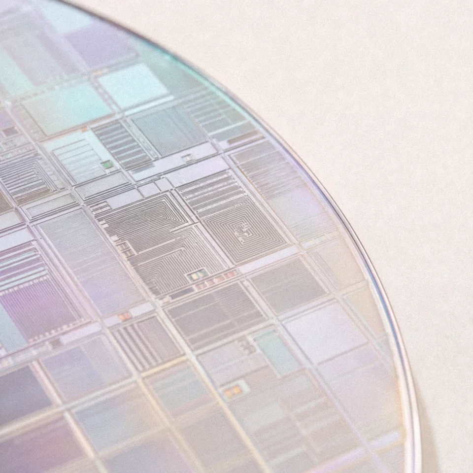 Edge of an iridescent silicon wafer on cream paper.